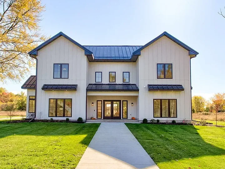 White modern farmhouse with a black metal roof and a front walkway