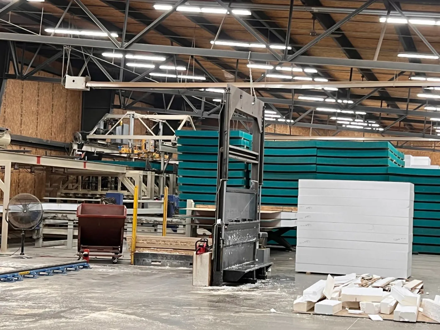 Panel plant floor with stacks of foam insulation panels and a panel press