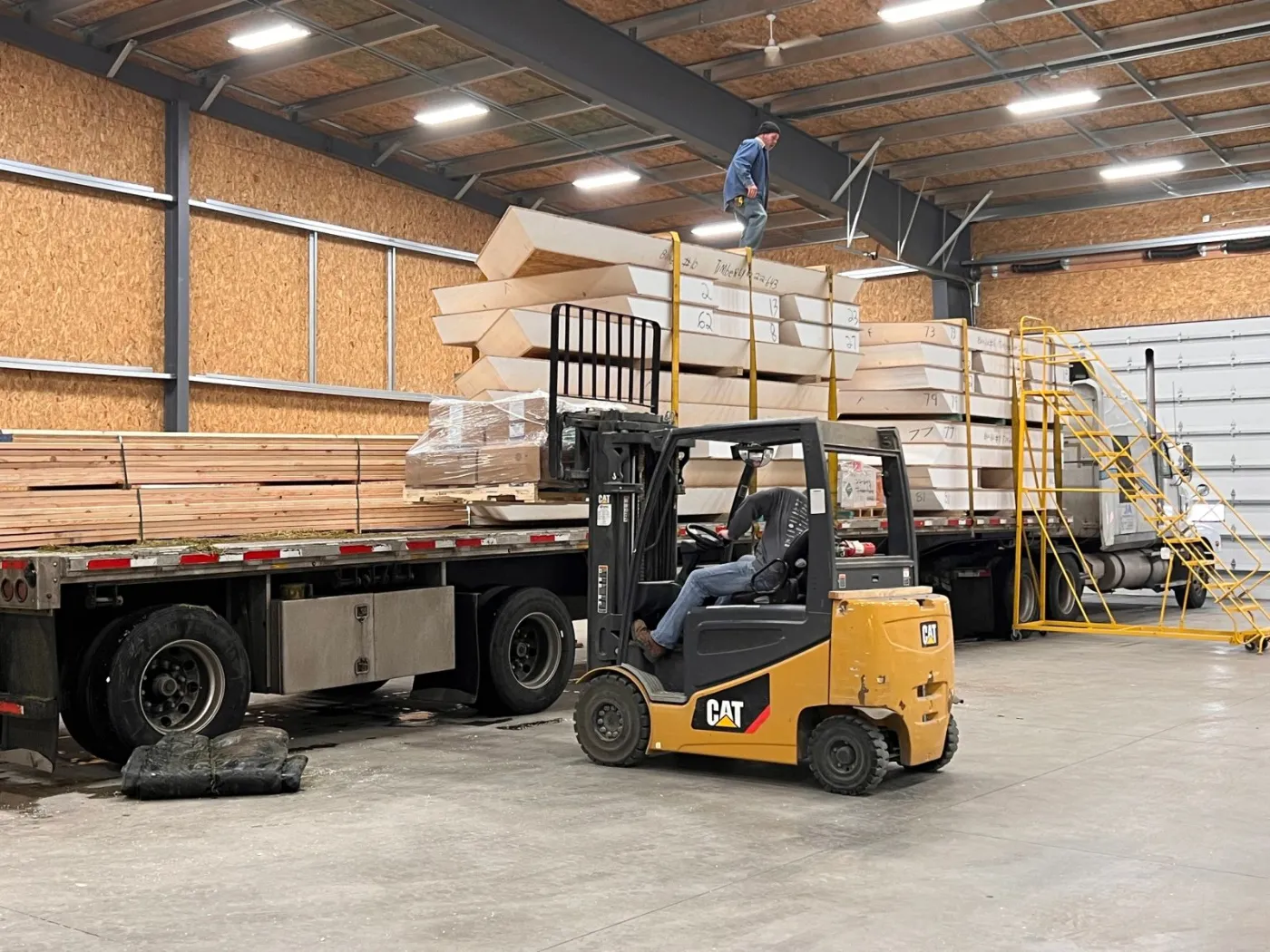 A forklift loading finished panels onto a flatbed truck