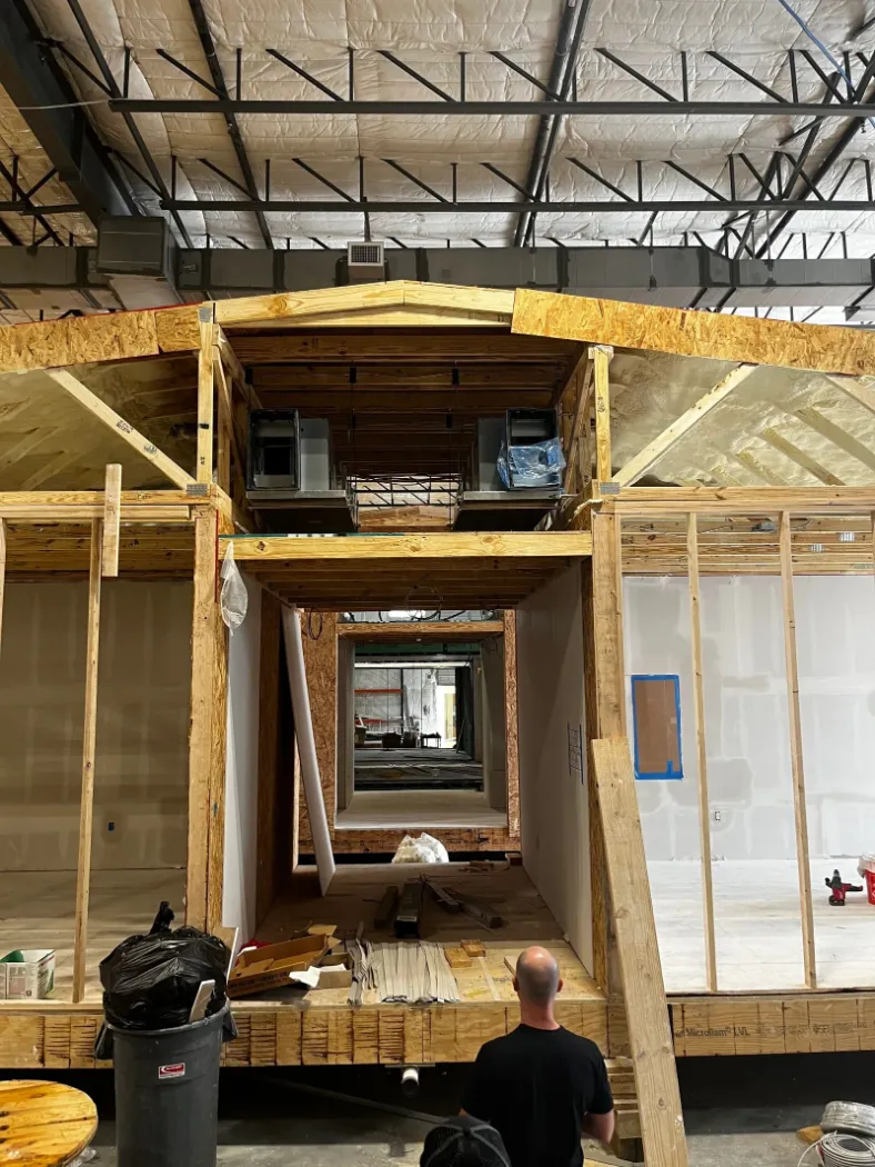 A framed module with a window opening, with a worker on the floor