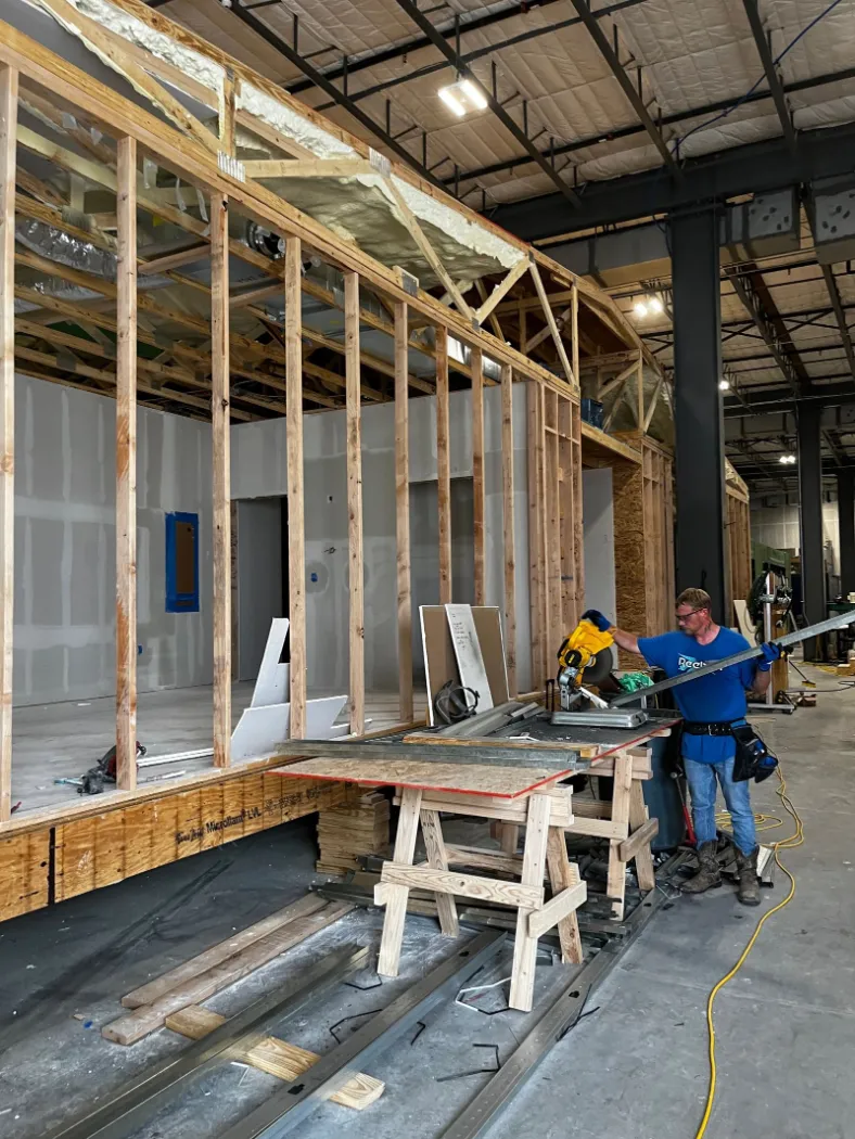 Workers framing module walls at a work table