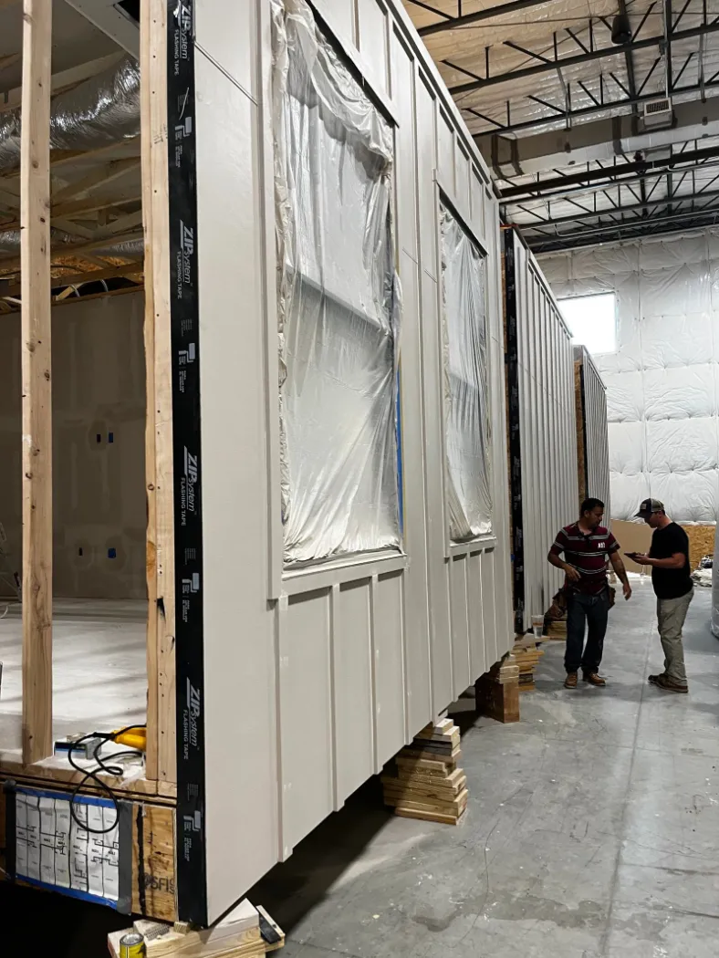 Module walls being closed in, with workers alongside