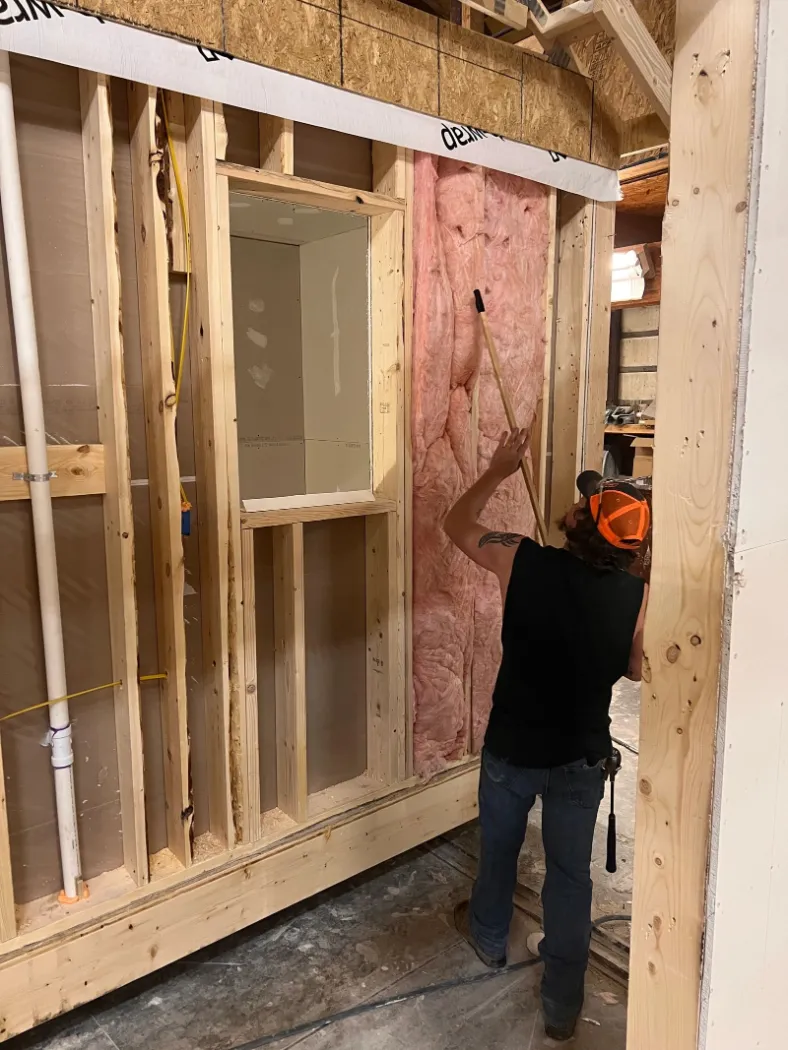 A worker installing insulation in a framed module wall