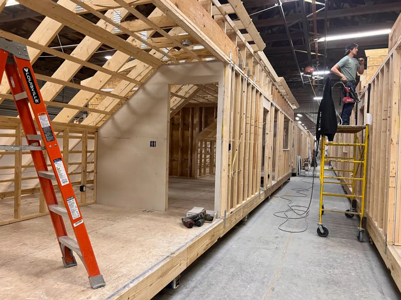 Roof framing and interior walls on a module, with a ladder and scaffold