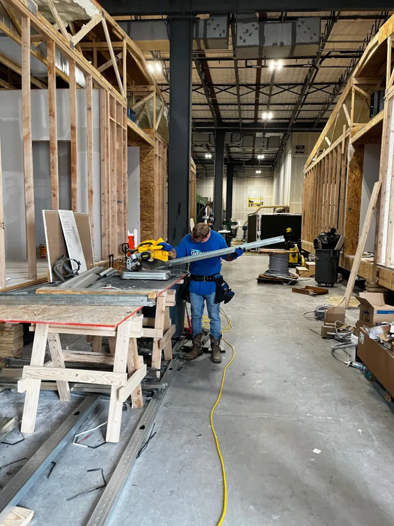 A factory production line of modules, with framing work at a sawhorse table