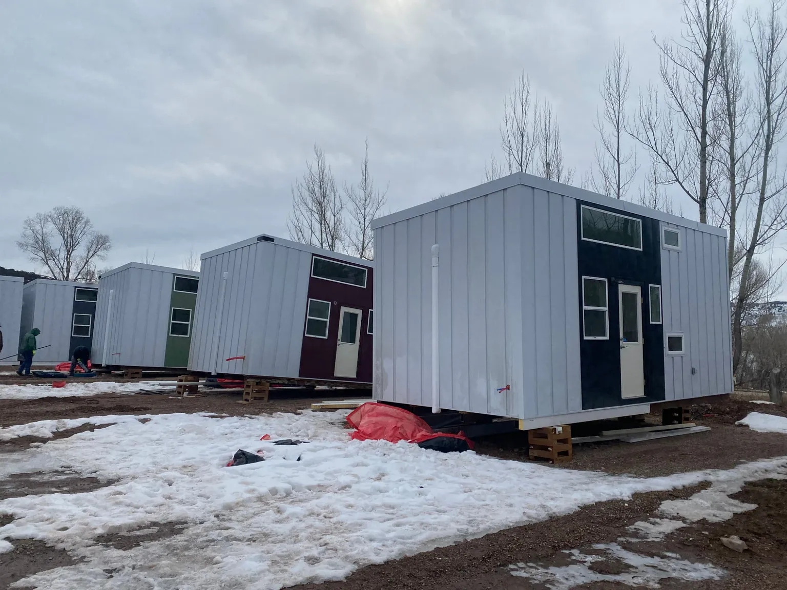 A row of units set in place on wood cribbing, with navy, burgundy, and green entry walls