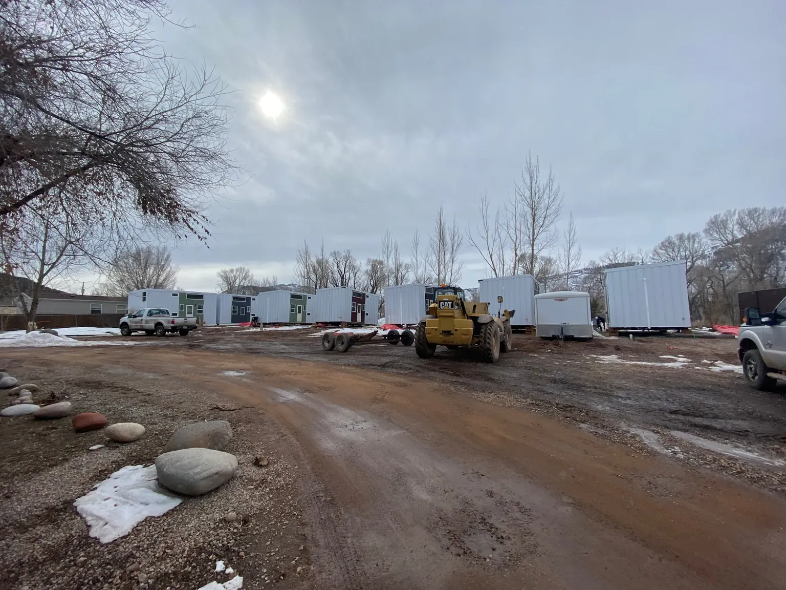 Wide view of the site with units in place, a telehandler, and work trucks