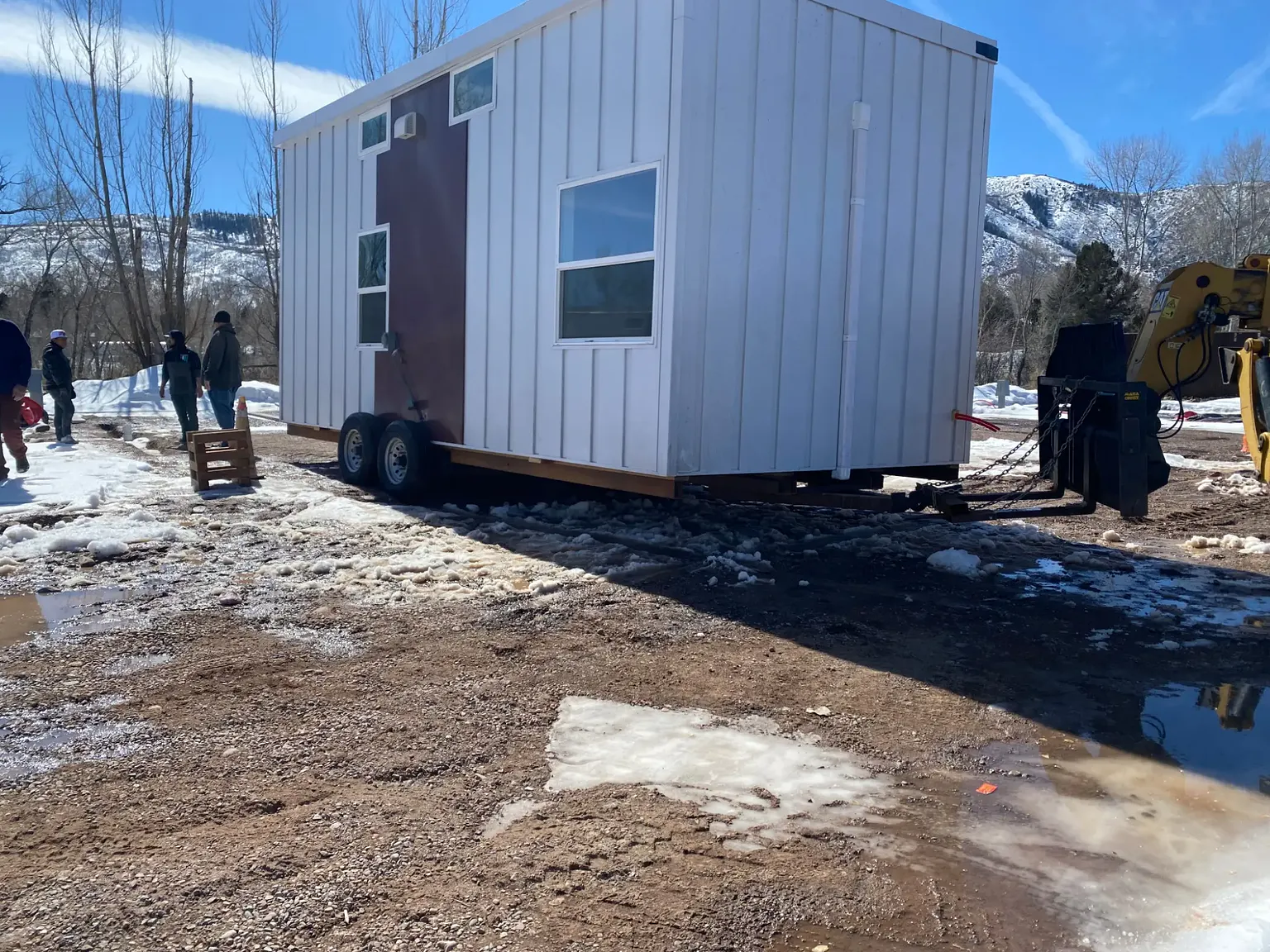 A unit on its trailer being moved into position by a telehandler, with snow-covered mountains behind