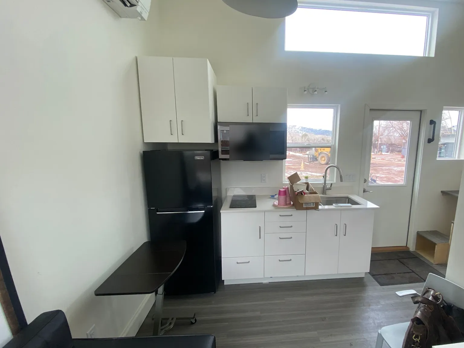 Kitchen with white cabinets, a black refrigerator, a cooktop, and a window toward the mountains