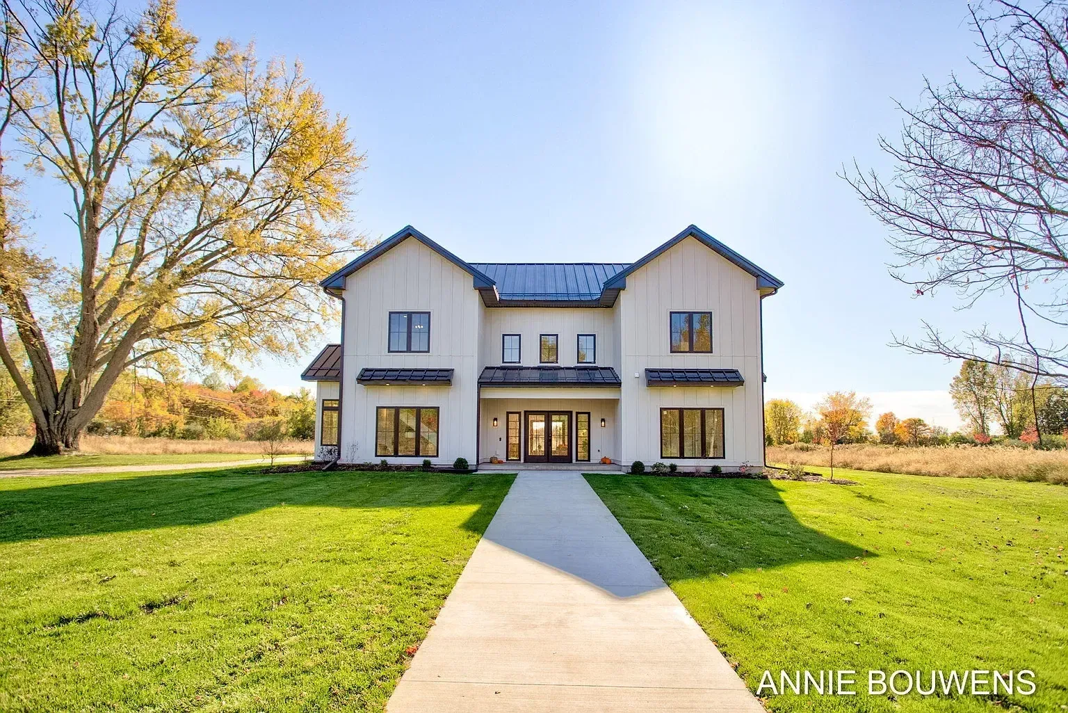 White modern farmhouse with black metal roof and front walkway