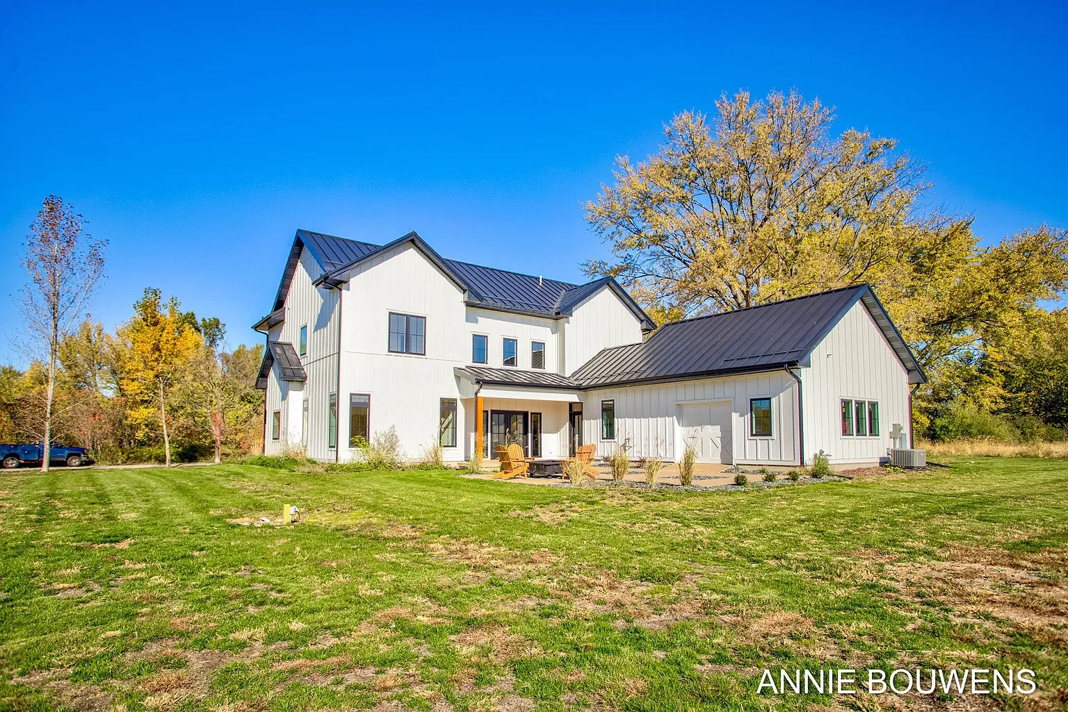 Rear of the home with lawn and mature trees in fall color