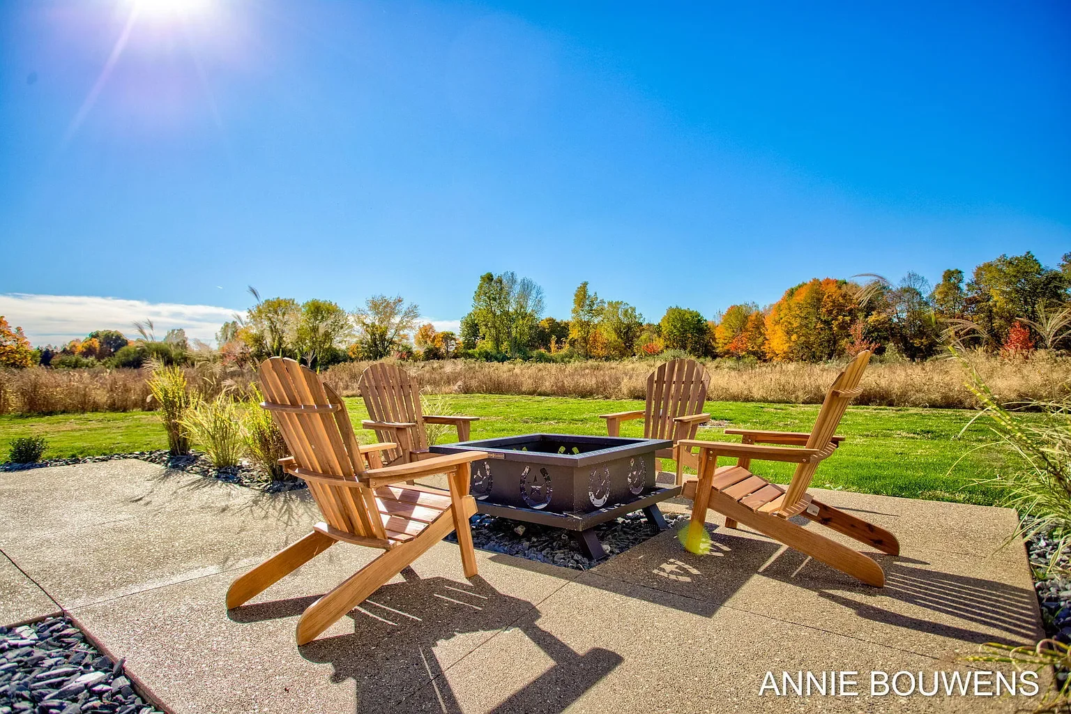 Backyard patio with fire pit and Adirondack chairs overlooking open land