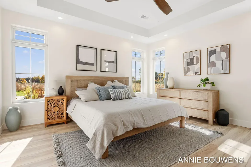 Primary bedroom with a tray ceiling, a wood bed, and corner windows