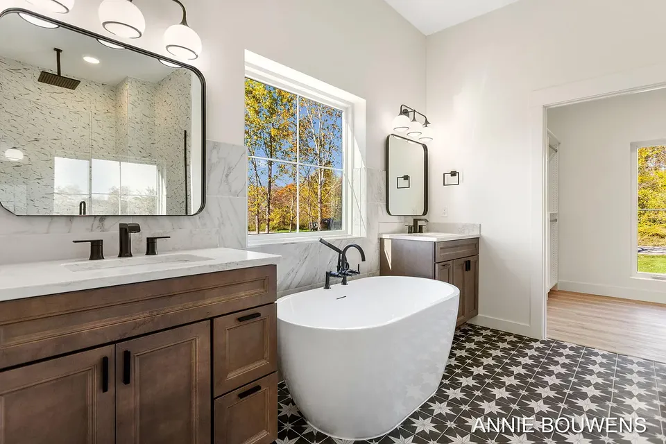 Primary bath with a freestanding tub, patterned floor tile, and a wood vanity