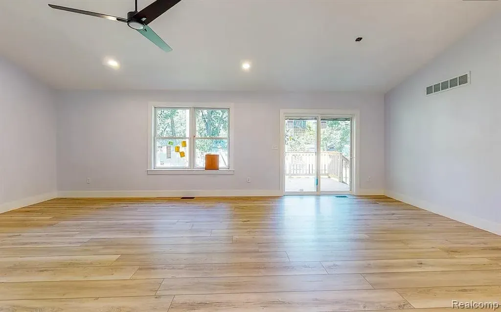 Living room with wood-look floors, a ceiling fan, and a sliding door to the back yard