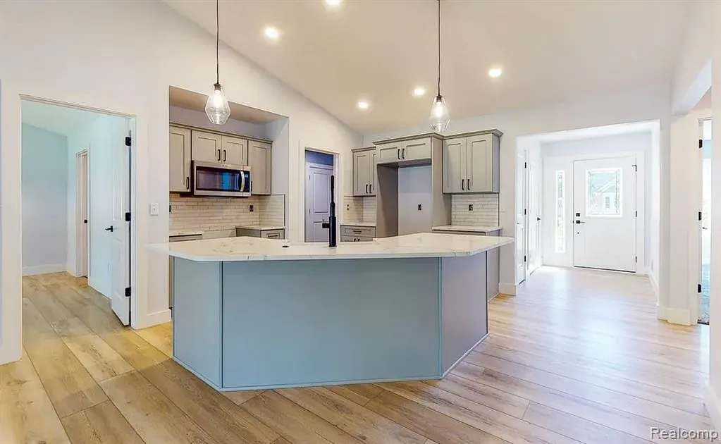 Kitchen with gray cabinets, a large island, and pendant lights