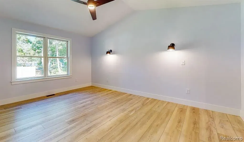 Primary bedroom with wood-look floors and two windows