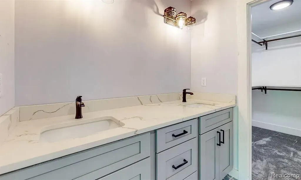 Primary bath with a gray vanity and a walk-in closet beyond