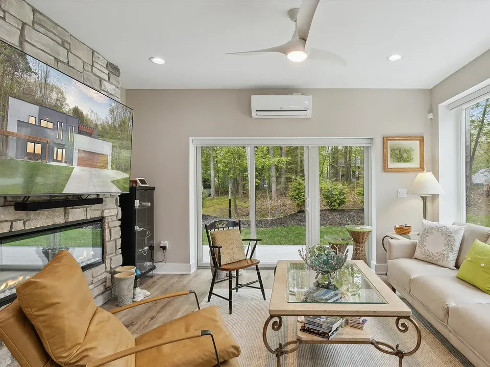 Living room with a stone fireplace wall and sliding doors to the patio