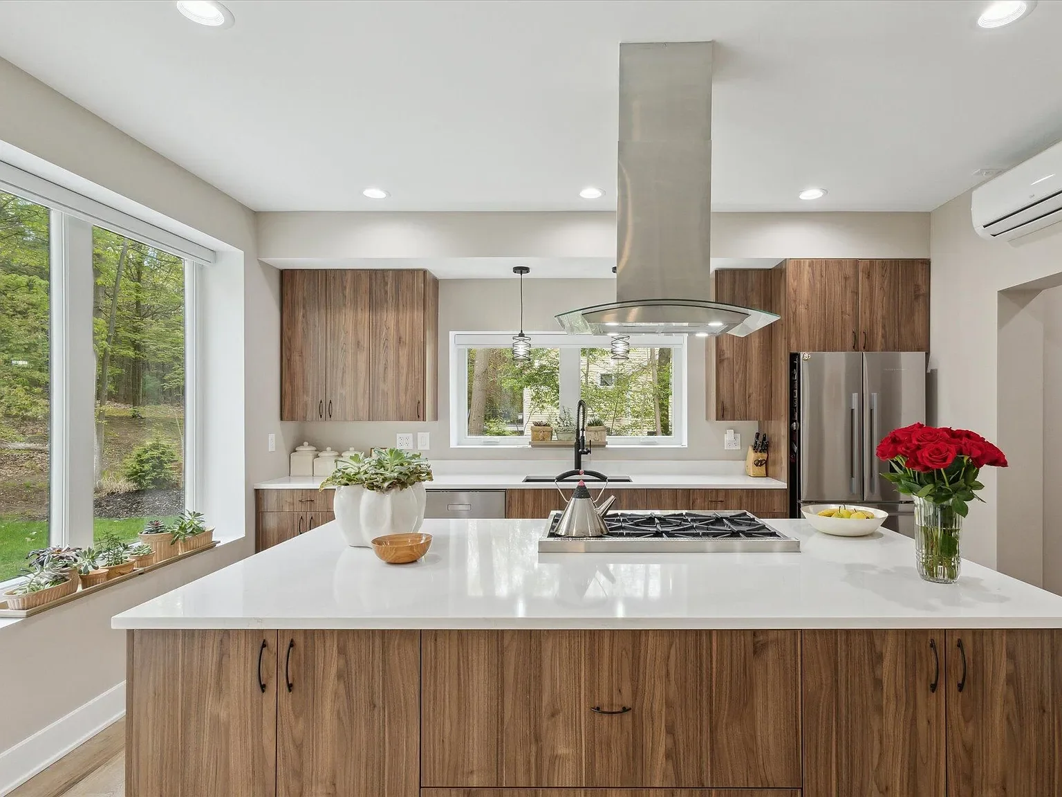 Kitchen with island cooktop, stainless hood, and wood cabinetry