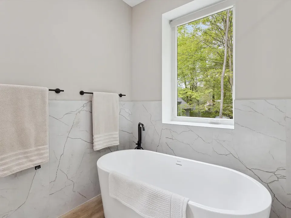 Primary bath with a freestanding tub and marble-look wall tile