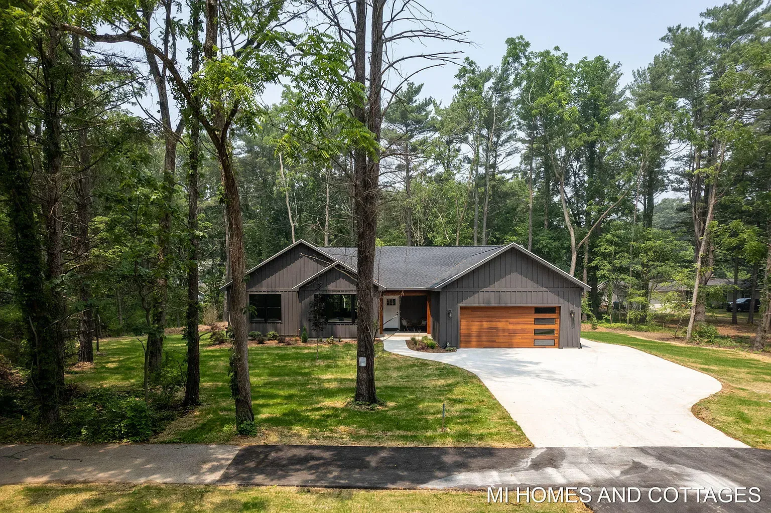 Aerial view of the home and driveway on a wooded lot