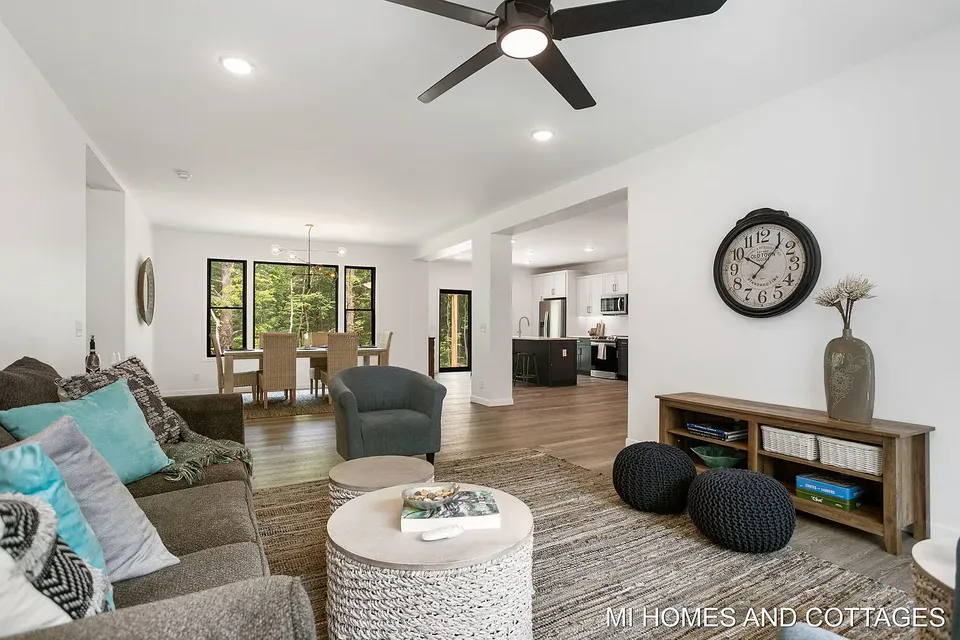 Living room with gray sofas, woven poufs, and black-framed windows
