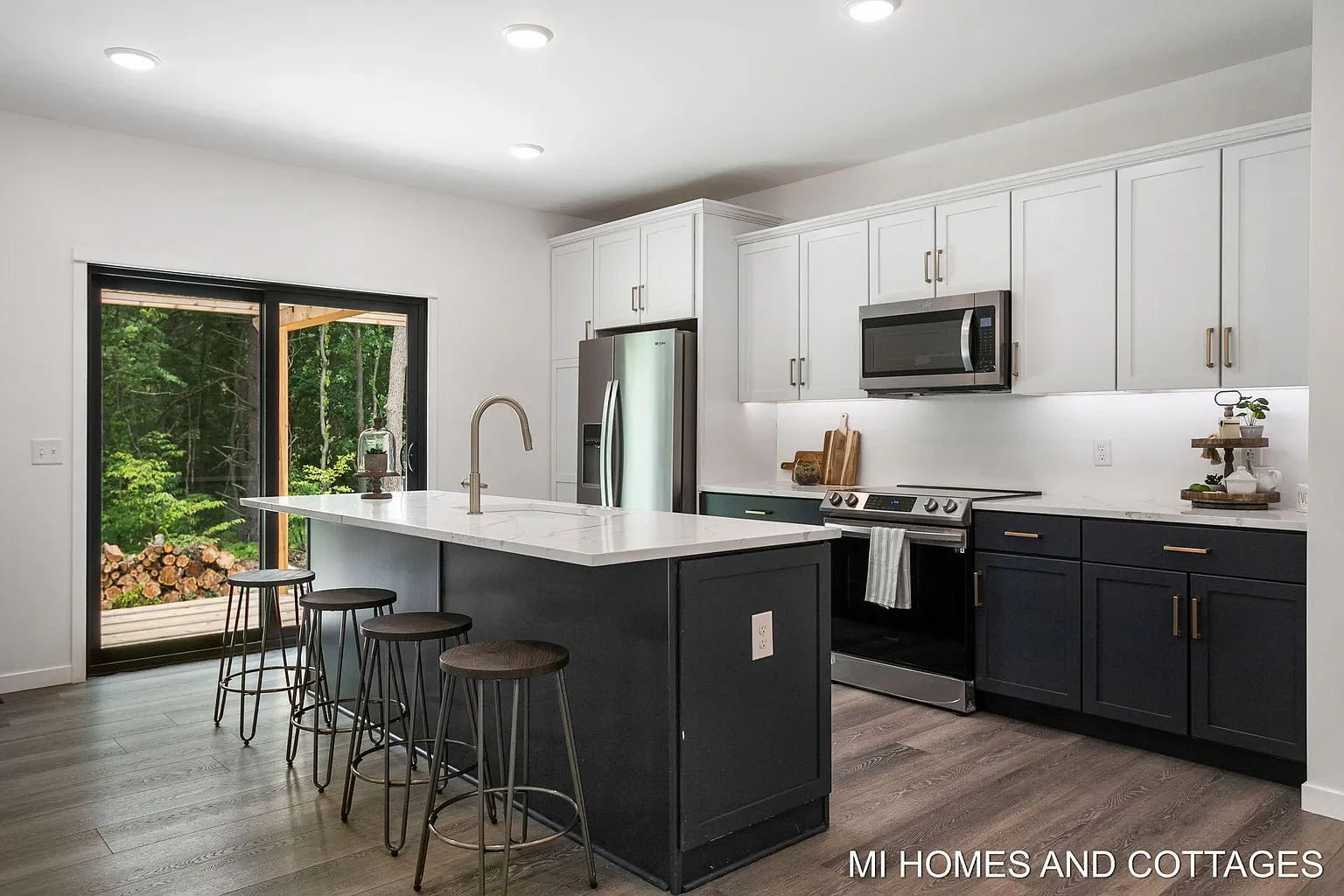Kitchen with white upper cabinets, dark island, and sliding door to the yard