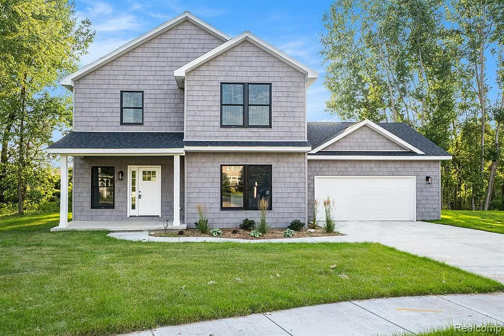 Two-story home with shake siding, a covered porch, and an attached garage
