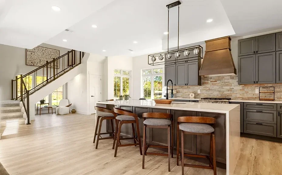 Open kitchen with gray cabinets, a stone backsplash, a copper range hood, and a large island with wood stools