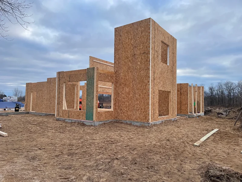 The same home during construction, with prefabricated wall panels standing on the new foundation