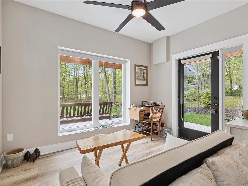 Den with a ceiling fan, a large window onto the covered porch, and a glass door to the yard