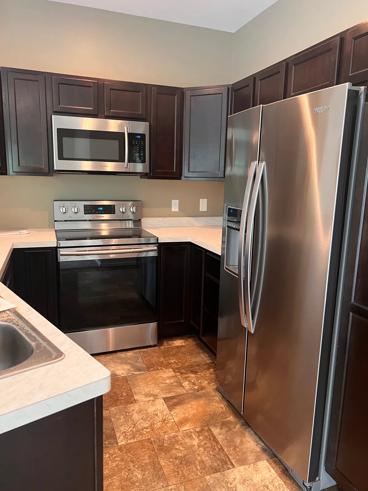 Kitchen with dark cabinets, stainless appliances, and tile flooring